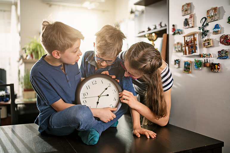 3 kids with a clock - daylight saving time