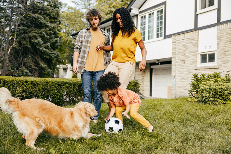 family playing outside with their soccer ball and dog