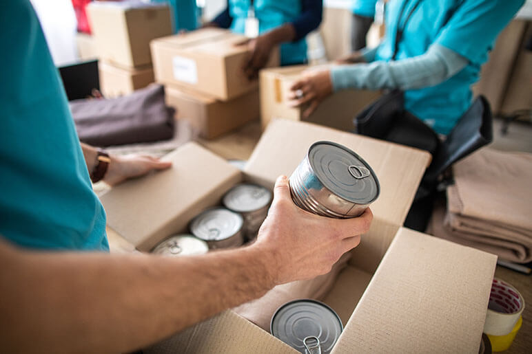 People boxing canned goods into cardboard boxes to help their community this holiday season