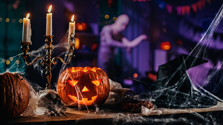 haunted house table with cobwebs and a jack-o-lantern and a mummy in the background