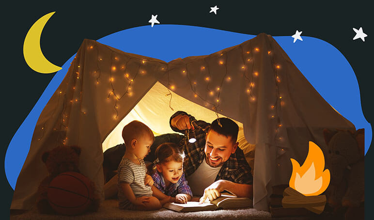 Dad with two young children inside a tent reading a book with a flashlight pointed at the book