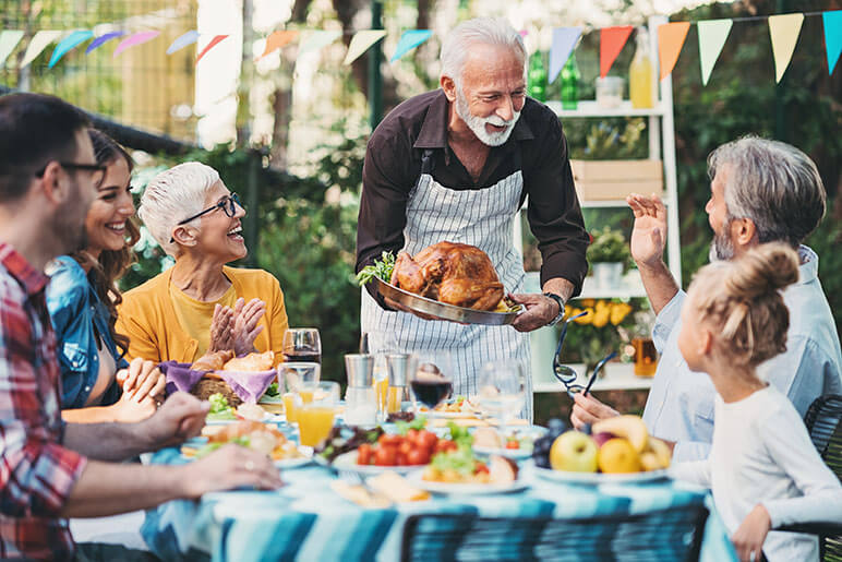 Small family gathering for Thanksgiving outdoors while an older gentleman is serving the family a Thanksgiving turkey