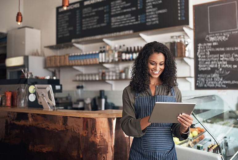 Younger woman with an iPad looking at business insurance options working at her small business