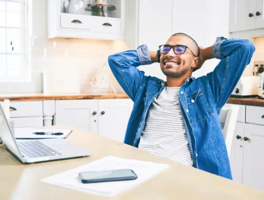 Men in blue jeans jacket and glasses reclining on chair happily after bundling his insurance and get discounted rates